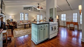 Una cocina amplia con una isla central, suelo de madera y un comedor con mesa y sillas.