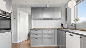 Eine moderne Küche mit grauen Schränken, einem eingebauten Backofen und einem Geschirrspüler.