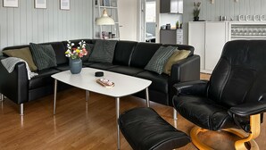 Ein modernes Wohnzimmer mit einem schwarzen Ledersofa, einem weißen Couchtisch und einem schwarzen Ledersessel mit Holzfuß.