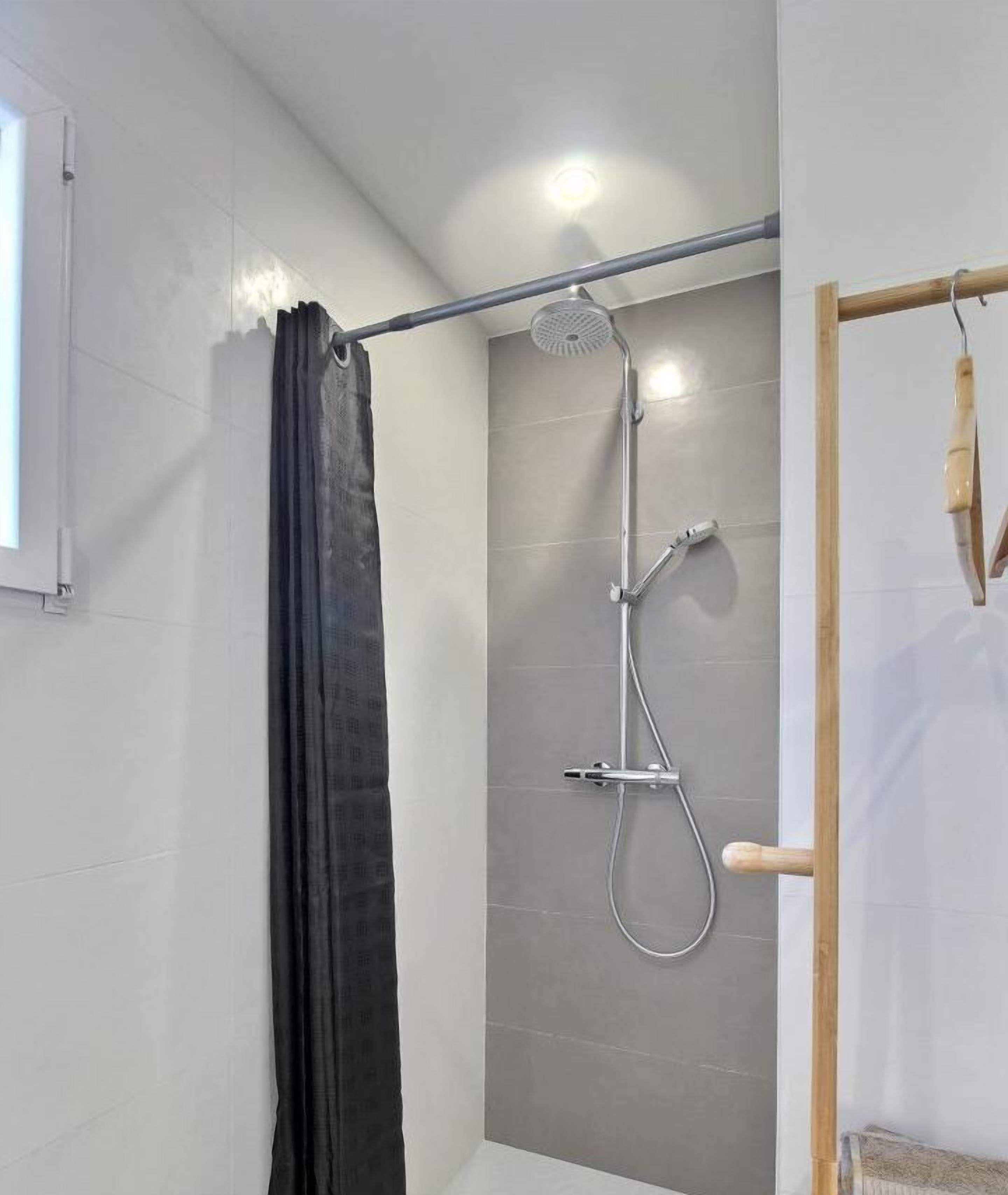 A shower area with a handheld showerhead, a wall-mounted rain showerhead, and a curtain.