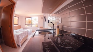 A modern kitchen with a built-in stove, a sink, and a window providing natural light. - Chocolate com Pimenta Edifício (João Pessoa)