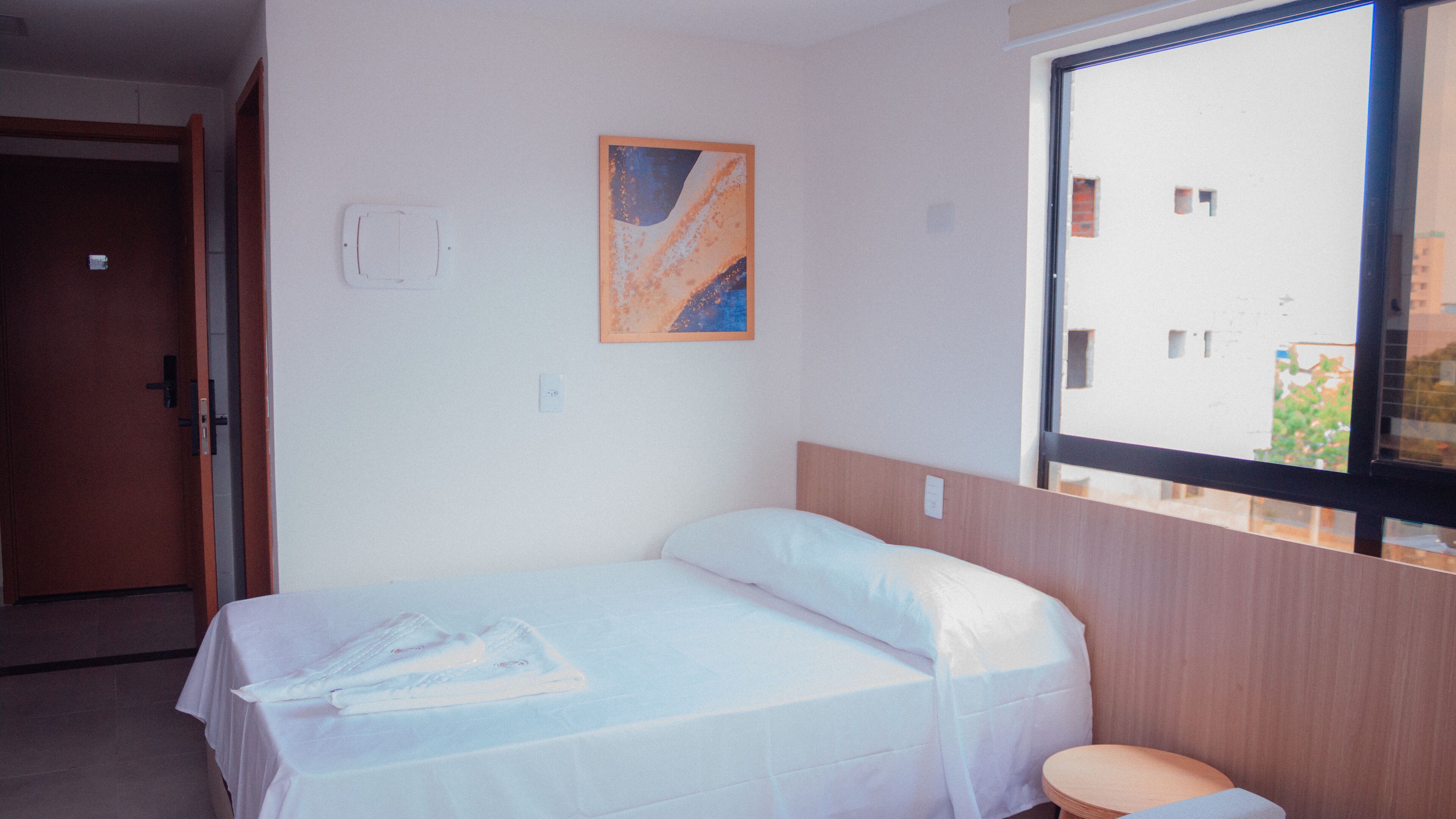 Una habitación de hotel con una cama, una ventana y un cuadro en la pared.