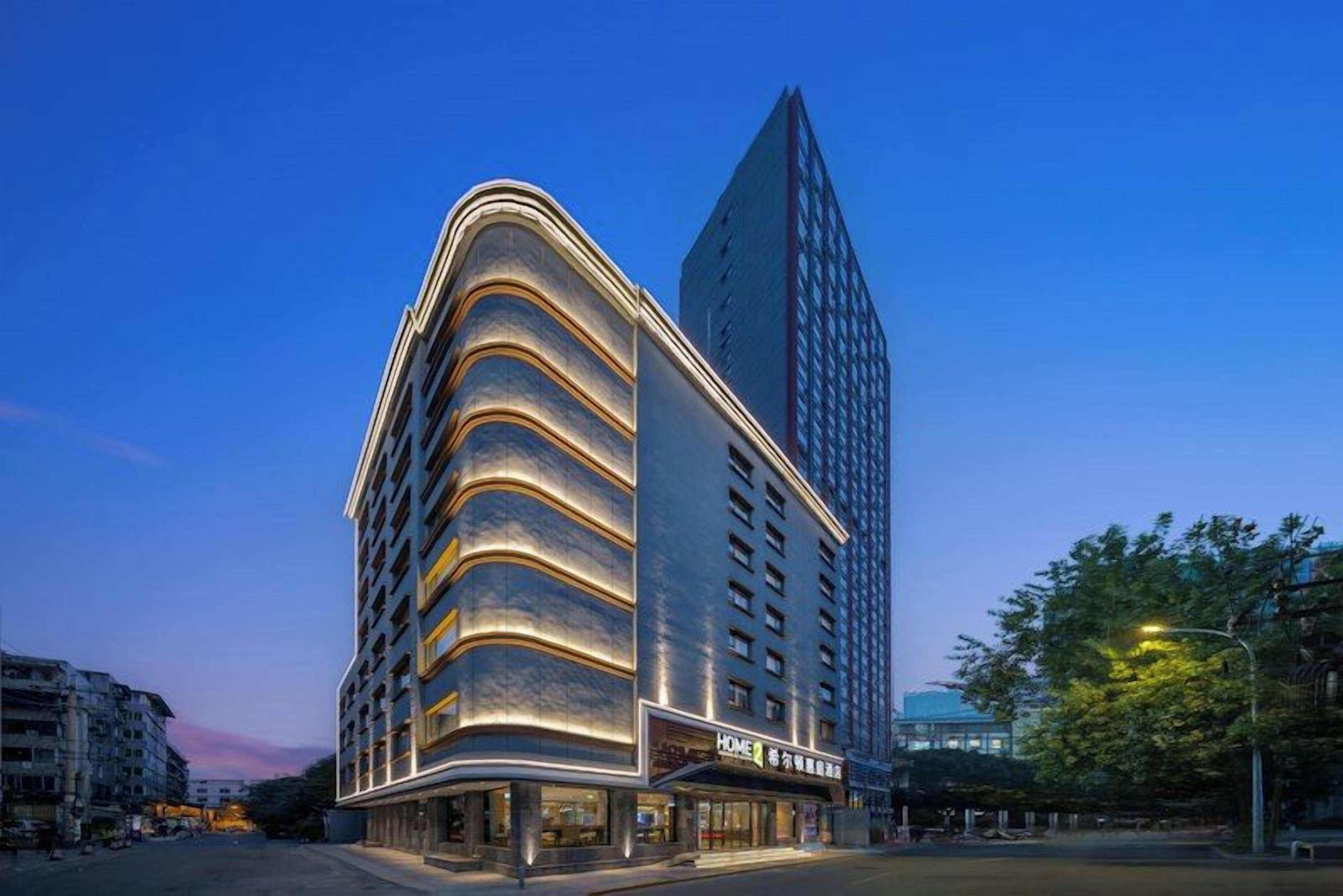 A multi-story hotel with a curved facade, a prominent entrance, and a tall adjacent building.