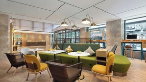 A modern interior with a green sofa, yellow chairs, and a bar area. - Home2 Suites by Hilton Chengdu Kuanzhai Alley (Chengdu)