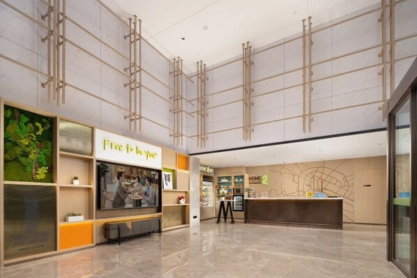 A spacious lobby with a reception desk, a 'Free to Live' sign, and a 'Home & Me' store. - Home2 Suites by Hilton Chengdu Kuanzhai Alley (Chengdu)