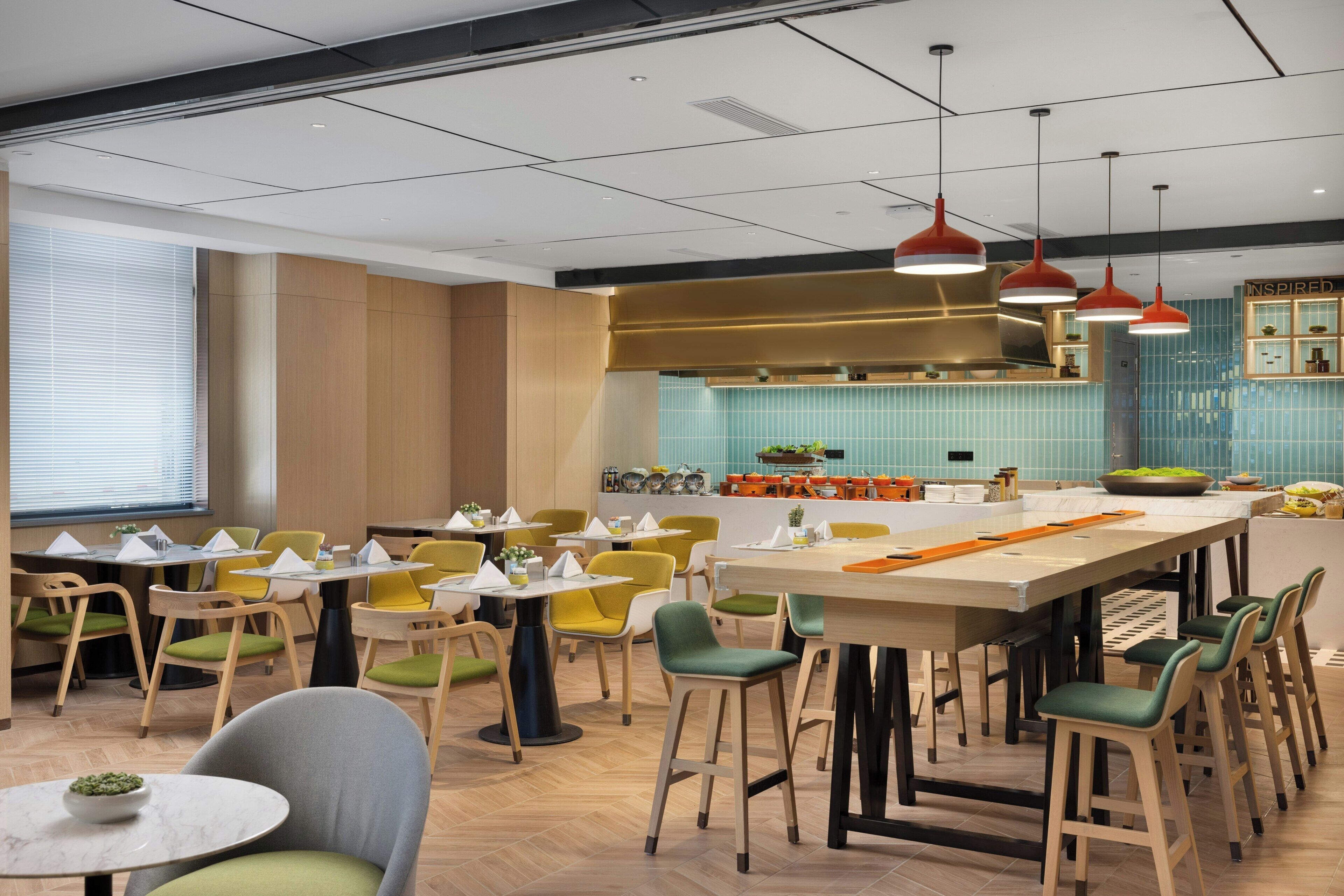A modern restaurant with a central island, multiple seating options, and a kitchen area visible in the background.