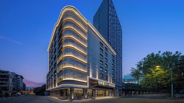 A modern hotel with a curved facade, a prominent entrance, and a tall adjacent building. - Home2 Suites by Hilton Chengdu Kuanzhai Alley (Chengdu)
