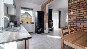 A modern kitchen with a built-in oven, a dining area with a wooden table, and a brick accent wall.