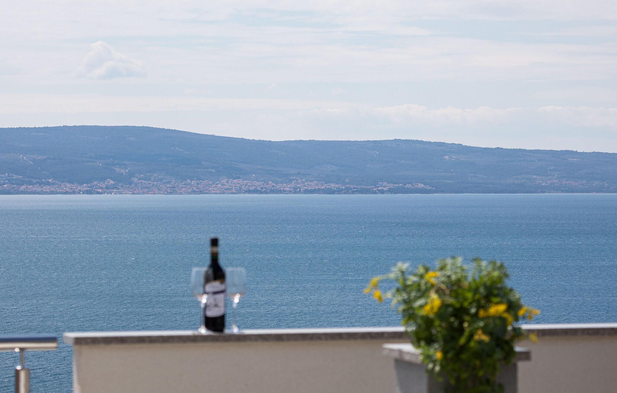 A balcony with a view of a large body of water and distant hills.