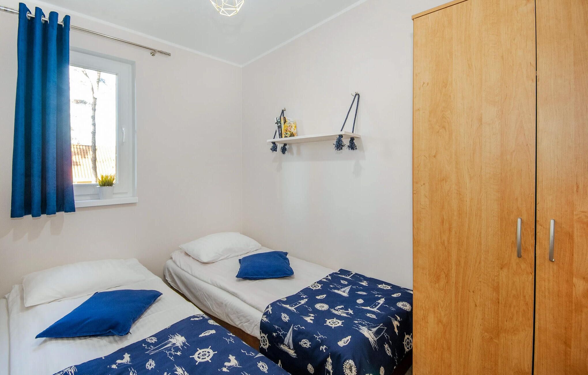 Ein Schlafzimmer mit zwei Betten, einem Holzschrank, einem Regal mit Dekoration und einem Fenster mit blauen Vorhängen.