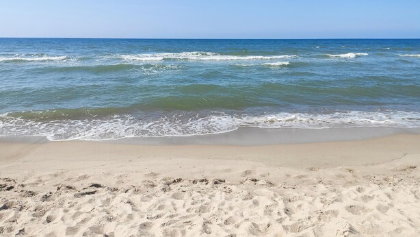 En strand med kristallklart blått vatten och en sandstrand.