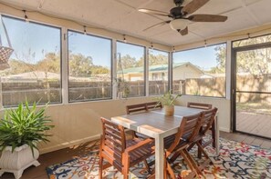 Enjoy a peaceful meal in this sunroom with a dining table and chairs, surrounded by a beautiful view of the outdoors.