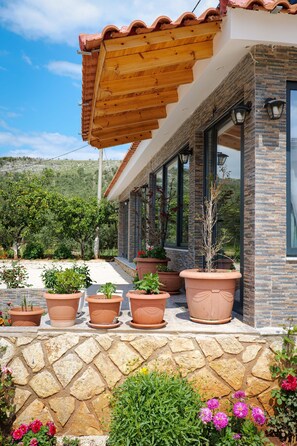 Una casa moderna con facciata in pietra, ampie finestre e una pergola in legno.