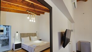 A bedroom with a bed, bedside tables, a TV, and a refrigerator.