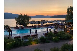 A resort pool area with lounge chairs and umbrellas, surrounded by a fence and greenery. - Whitefish Under the Big Sky Getaway (Whitefish)