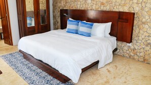 Un dormitorio con una cama grande, un armario de madera y una pared de piedra.