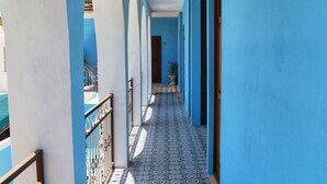 Un pasillo con paredes azules y baldosas de suelo estampadas, que conduce a una puerta al final.