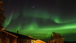 Una casa con un camino ben visibile, un piccolo portico e un cielo notturno stellato.