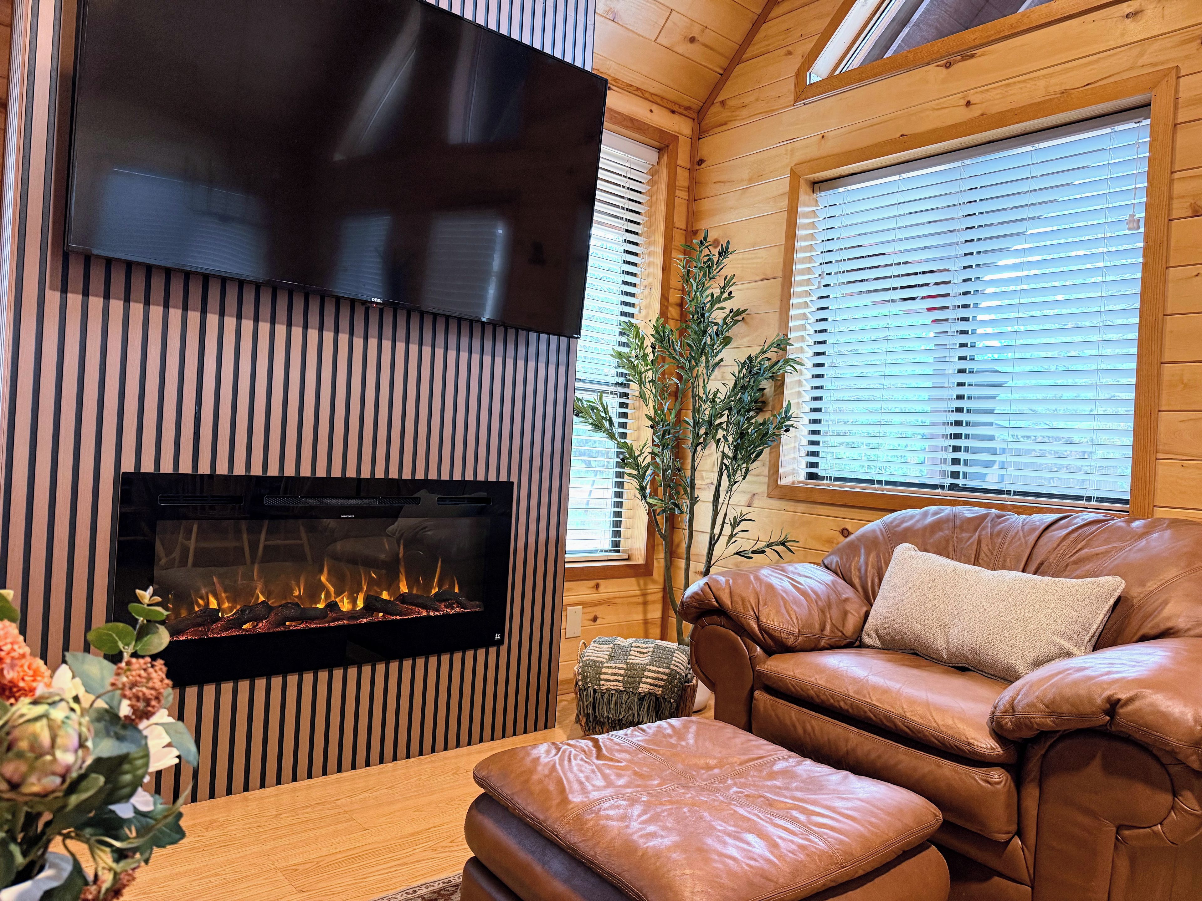 Cozy fireside lounge with leather seating, big TV, and warm cabin charm