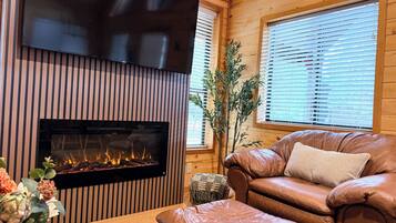 Cozy fireside lounge with leather seating, big TV, and warm cabin charm