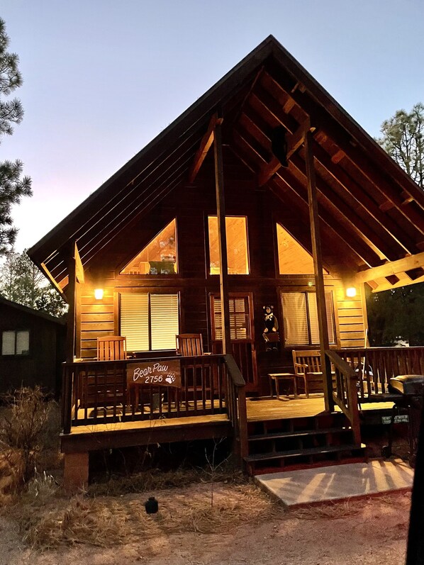 A wooden cabin with a porch, a small deck, and a mailbox.