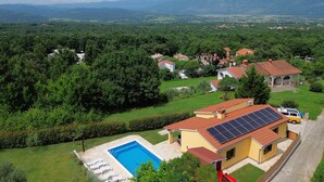 Un quartier résidentiel doté d’une piscine, de panneaux solaires et de maisons aux toits recouverts de tuiles rouges.