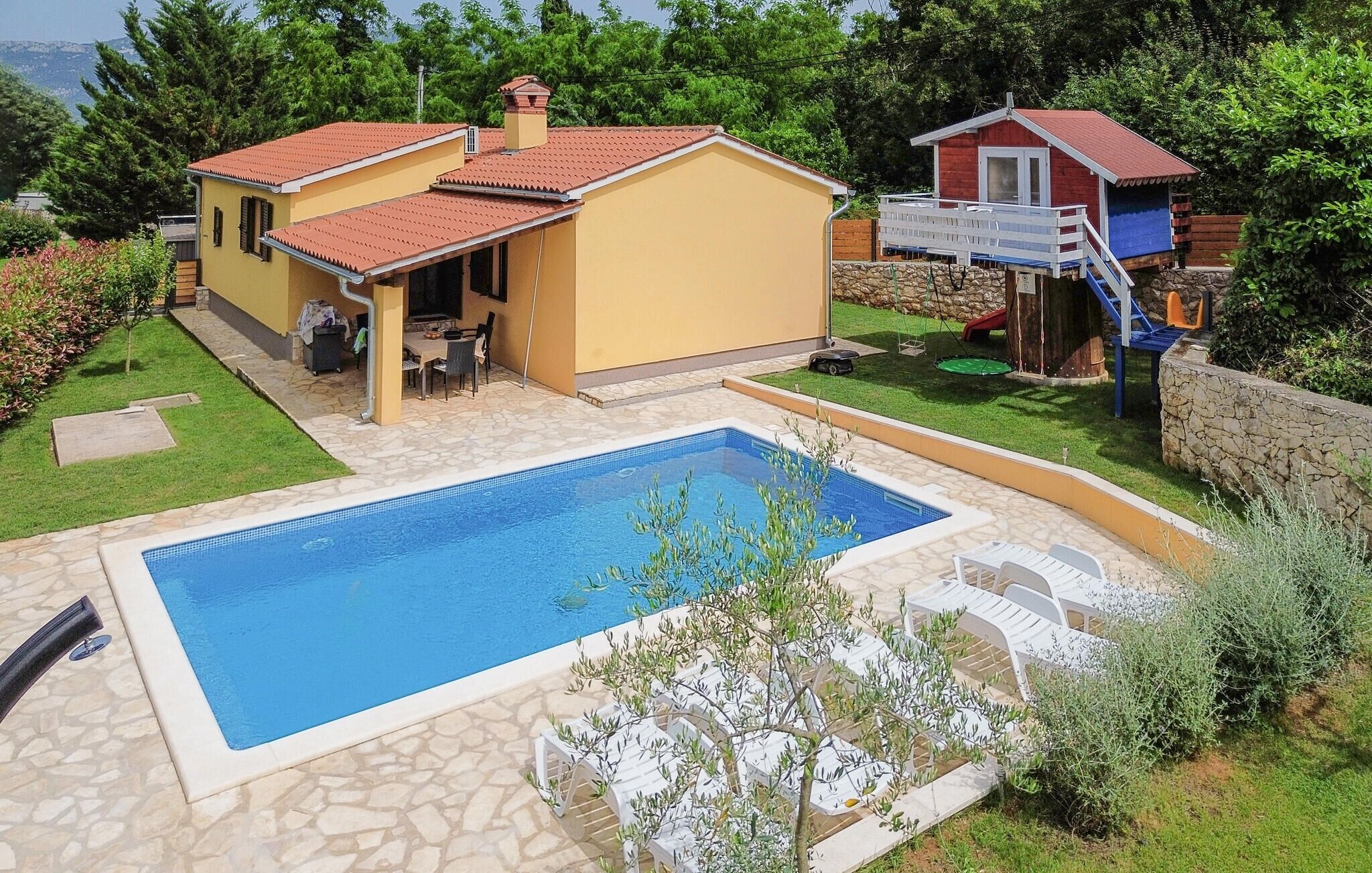 Une propriété résidentielle dotée d’une piscine, d’un patio avec mobilier d’extérieur et d’un petit espace de jeux avec un toboggan.