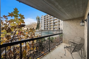 Enjoy the city view from this balcony with a metal railing and two chairs.