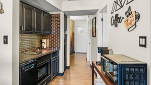Una cocina moderna con armarios oscuros, un salpicadero de ladrillo y una obra de arte con temática de café.