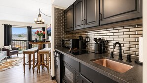 Una cocina moderna con armarios oscuros, encimera negra y pileta de cobre.