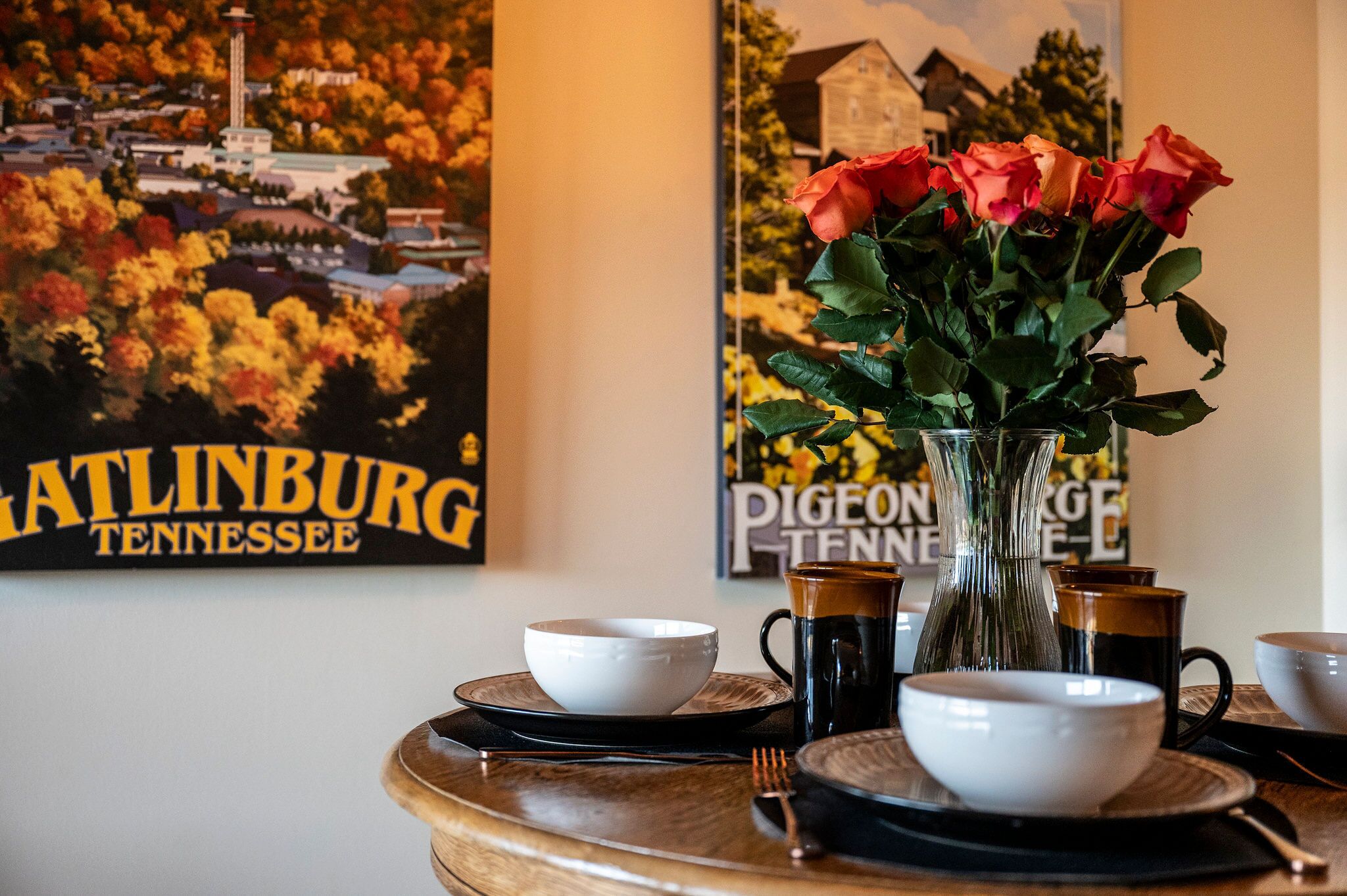 A dining table with a vase of roses, a coffee mug, and a bowl set on a wooden table.