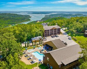 A hotel with a swimming pool, outdoor seating, and a view of a lake.