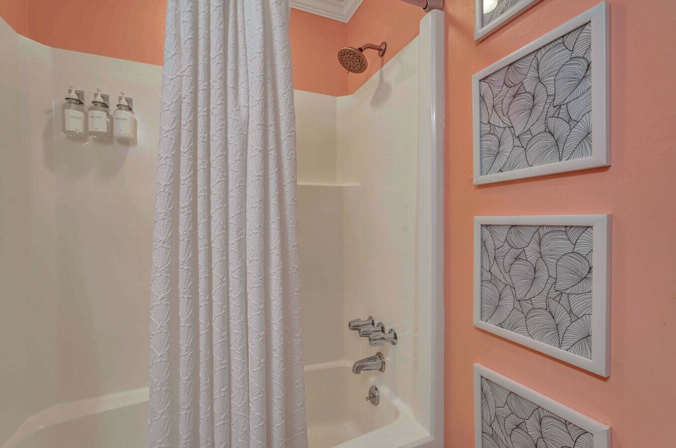 A bathroom with a bathtub, a shower, and three framed wall art pieces.