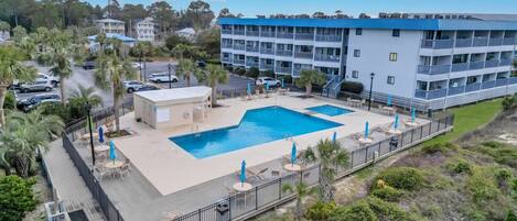 Un hôtel doté d’une piscine, d’un espace extérieur aménagé et d’un bâtiment à plusieurs étages avec des balcons.