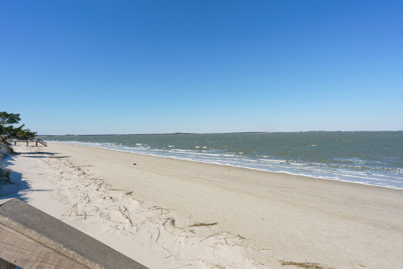 A beach with a wooden walkway and a clear sky.