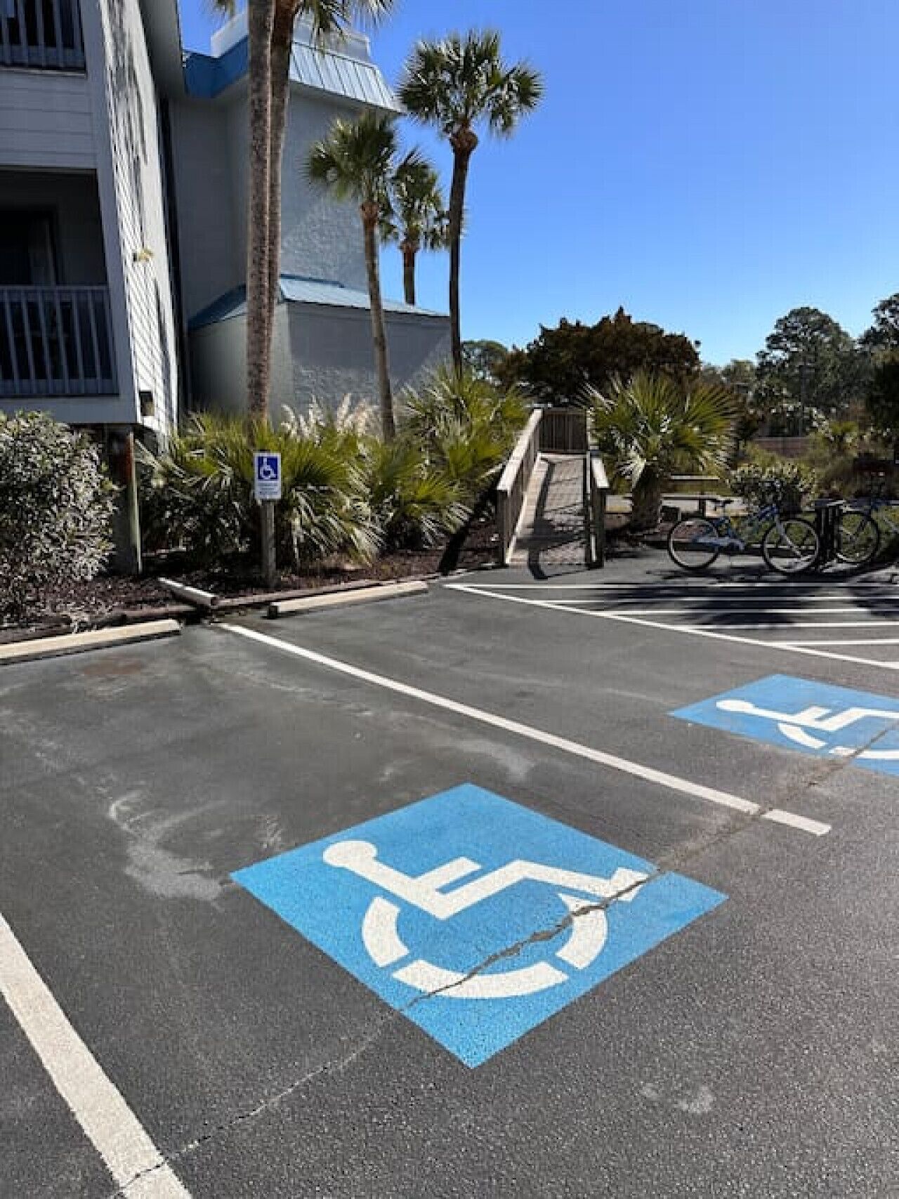 A parking lot with blue handicapped parking spaces, a wheelchair symbol, and a building with a blue and white facade.