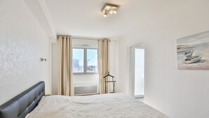 Ein Schlafzimmer mit einem Bett, einem Fenster, einer Heizung und einem Bild an der Wand.