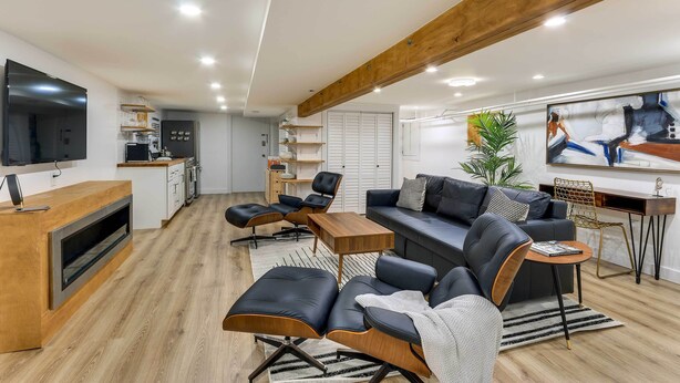 Una sala de estar moderna con un sofá, sillas, una mesa de centro y un televisor.