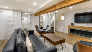 Una sala de estar moderna con un sofá, una mesa de centro y un televisor montado en la pared.