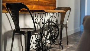 Un rincón comedor con un banco de madera y sillas de metal con diseños elaborados.