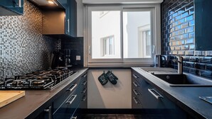 Una cocina moderna con una isla central, salpicadero de azulejos negros y electrodomésticos de acero inoxidable.