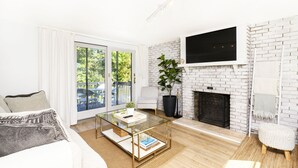 Een moderne woonkamer met een glazen salontafel, een witte bank en een open haard.