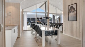 Una zona de menjador moderna amb una taula llarga, cadires i lluminàries penjants.