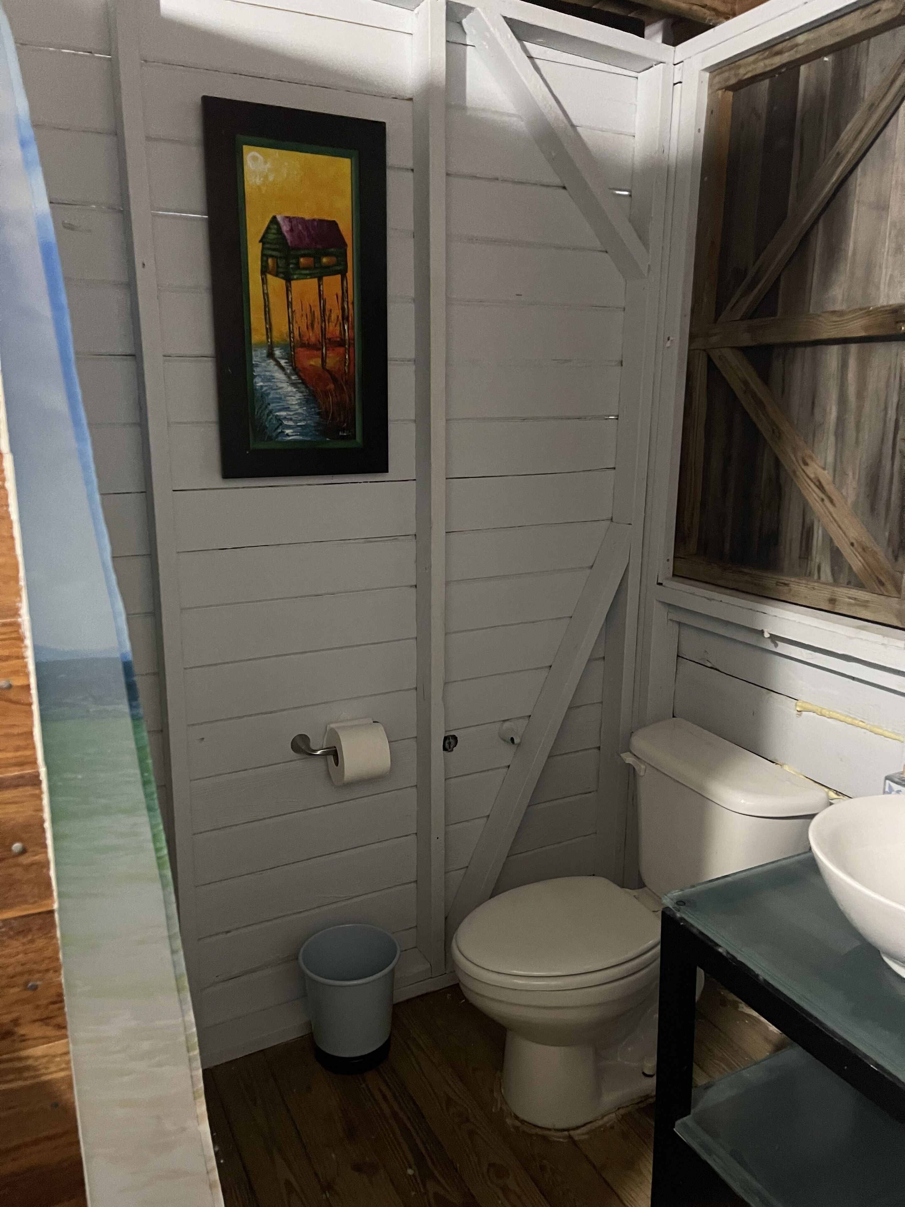 Ein kleines, kompaktes Badezimmer mit Toilette, Waschbecken und einem gerahmten Bild an der Wand.