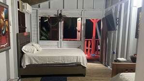 A room with a wooden floor, a bed with white bedding, a small table, and a television. - Studio facing the sea and only 15 minutes from the public ferry (Fajardo)