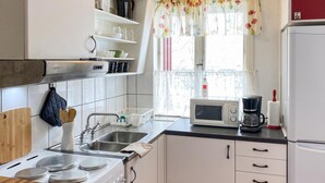 A kitchen with white cabinets, a stove, a sink, a microwave, and a refrigerator.