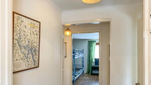 A hallway with a map on the wall, a bunk bed in the background, and a door leading to another room.