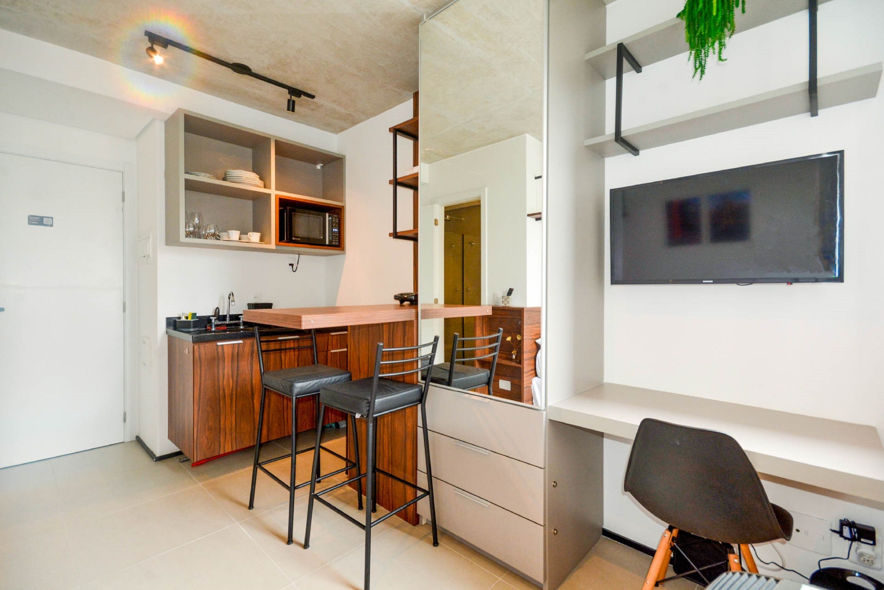Een moderne keuken met een bar, een magnetron en een flatscreen televisie aan de muur.