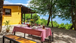 A table set outdoors with a checkered tablecloth, surrounded by natural scenery and a view of the sea. - Amazing home in Lovran (Lovran)