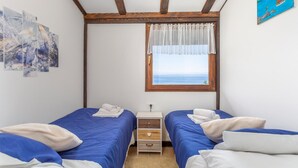 A bedroom with two beds, a window with a view of the sea, and a small bedside table with a lamp. - Amazing home in Lovran (Lovran)